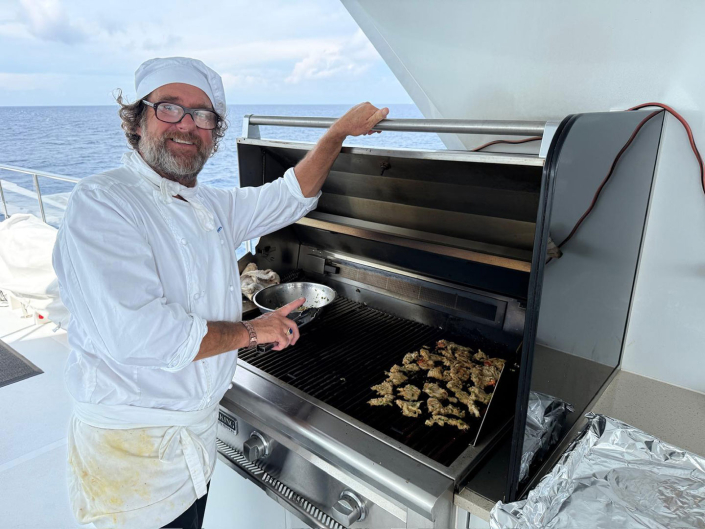 Chef Jim Ruch grilling fresh Bahamian local Conch off Georgetown Exumas